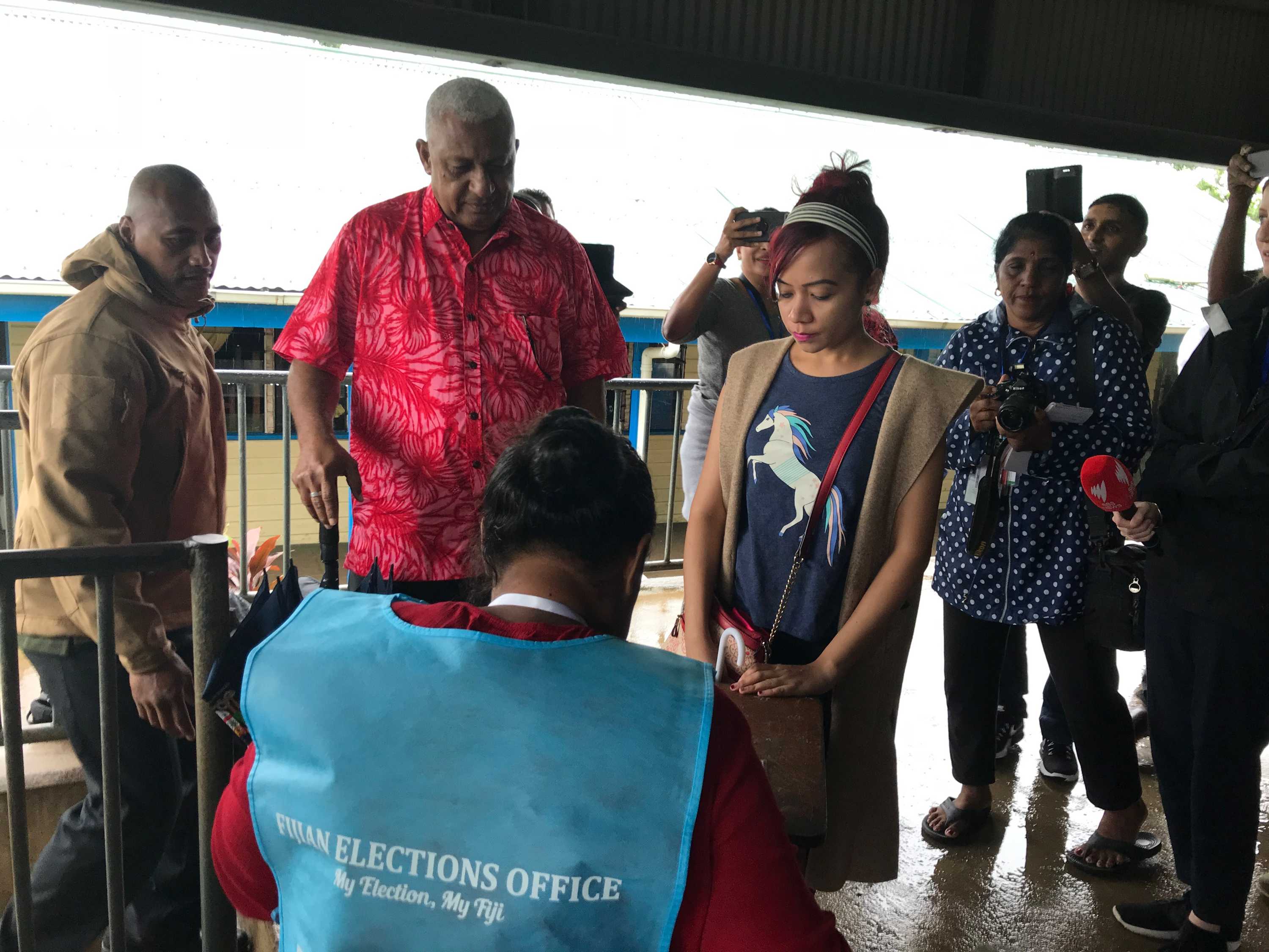 斐济总理弗兰克拜尼马拉马在 2018 年大选期间的一个投票站。记者正在给他拍照。